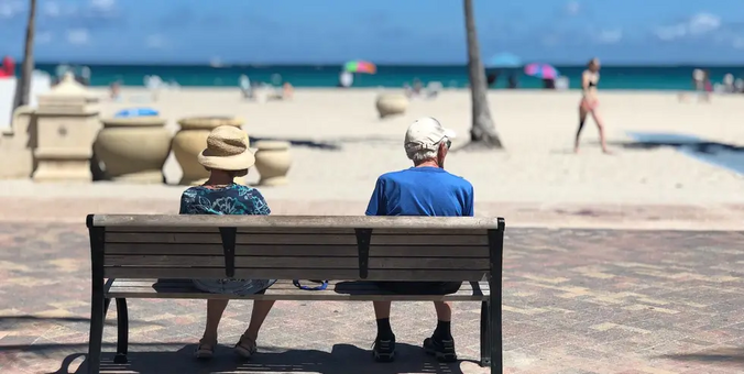 Two retirees are sitting on the seashore.