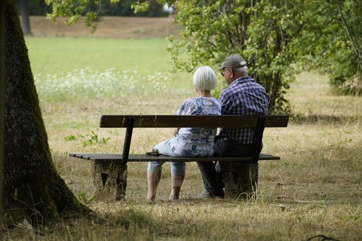 Elderly couple sitting in the park enjoying their tax deduction