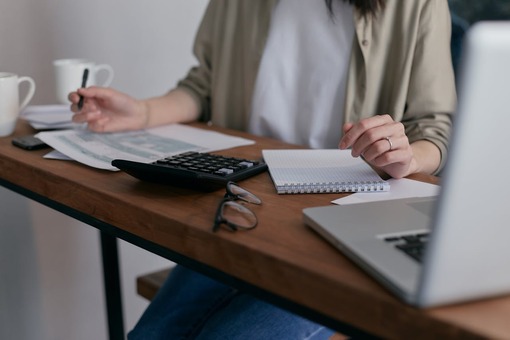 Woman handling paperwork, tax forms, laptop, desk, photo